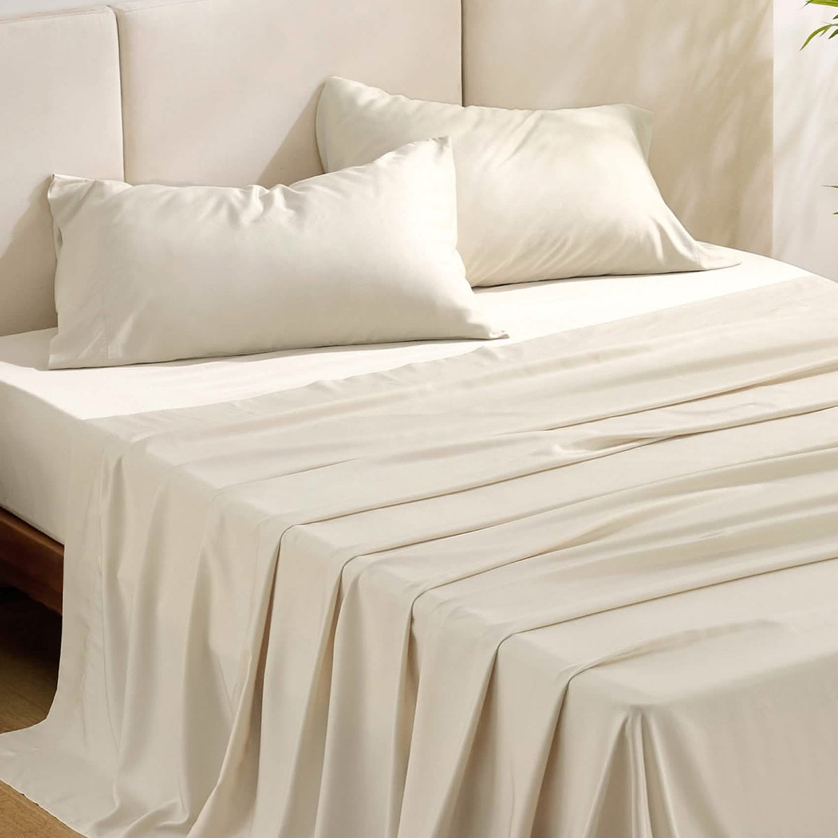Beige GentleSoft rayon from bamboo sheet set with two pillowcases on a bed, showcasing silky texture and drape.