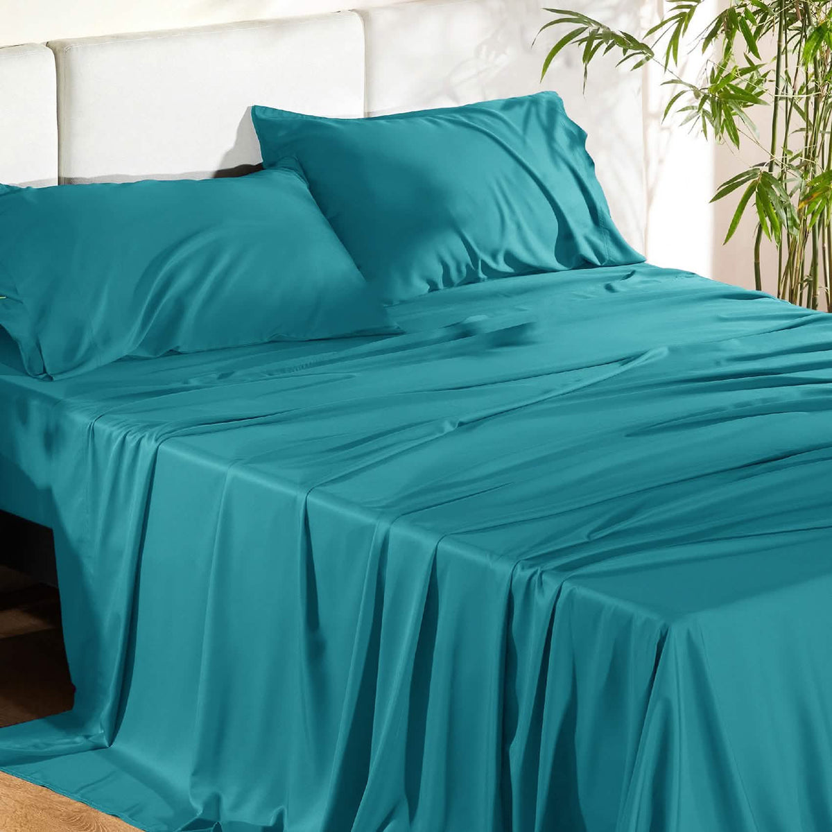 Teal blue GentleSoft rayon from bamboo sheet set with pillowcases on a bed, showing silky smooth texture and elegant drape.