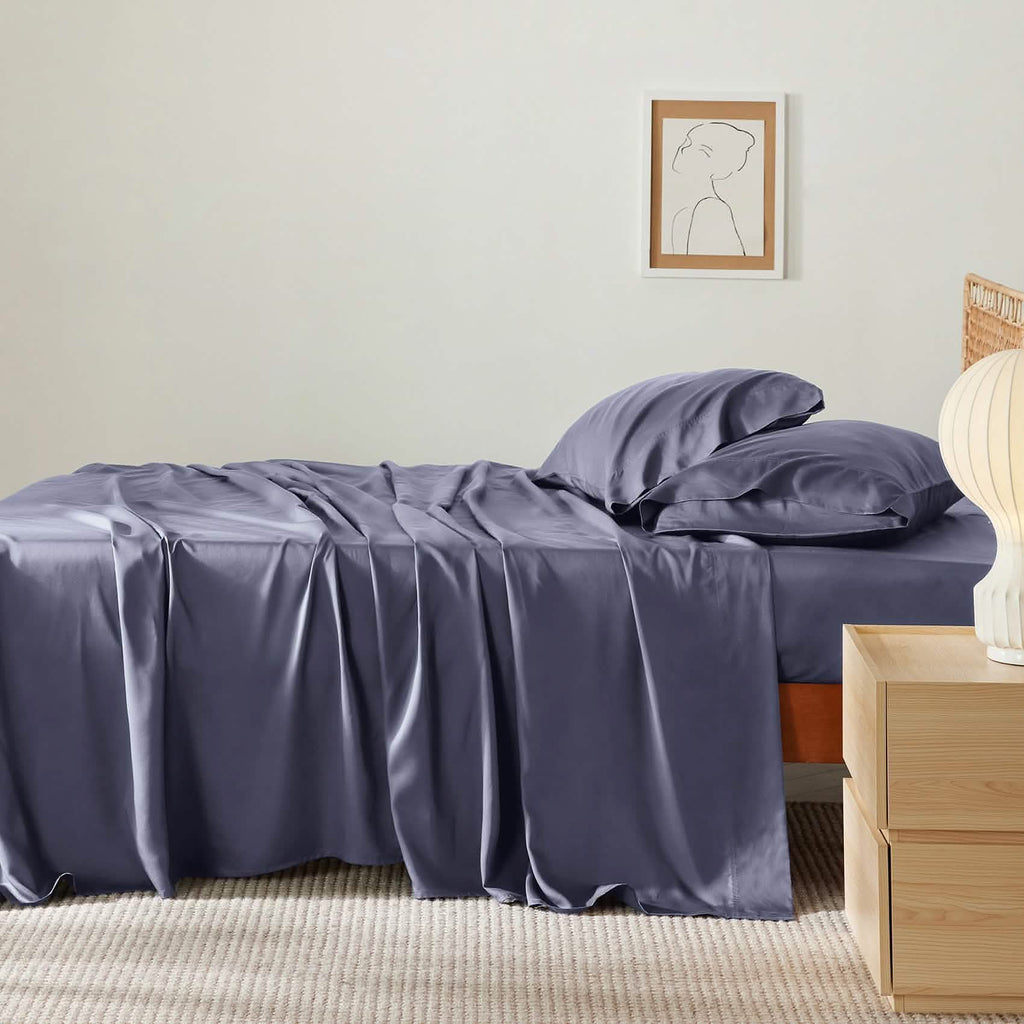 Muted lavender-gray rayon bamboo sheet set on bed, showing silky texture and drape.