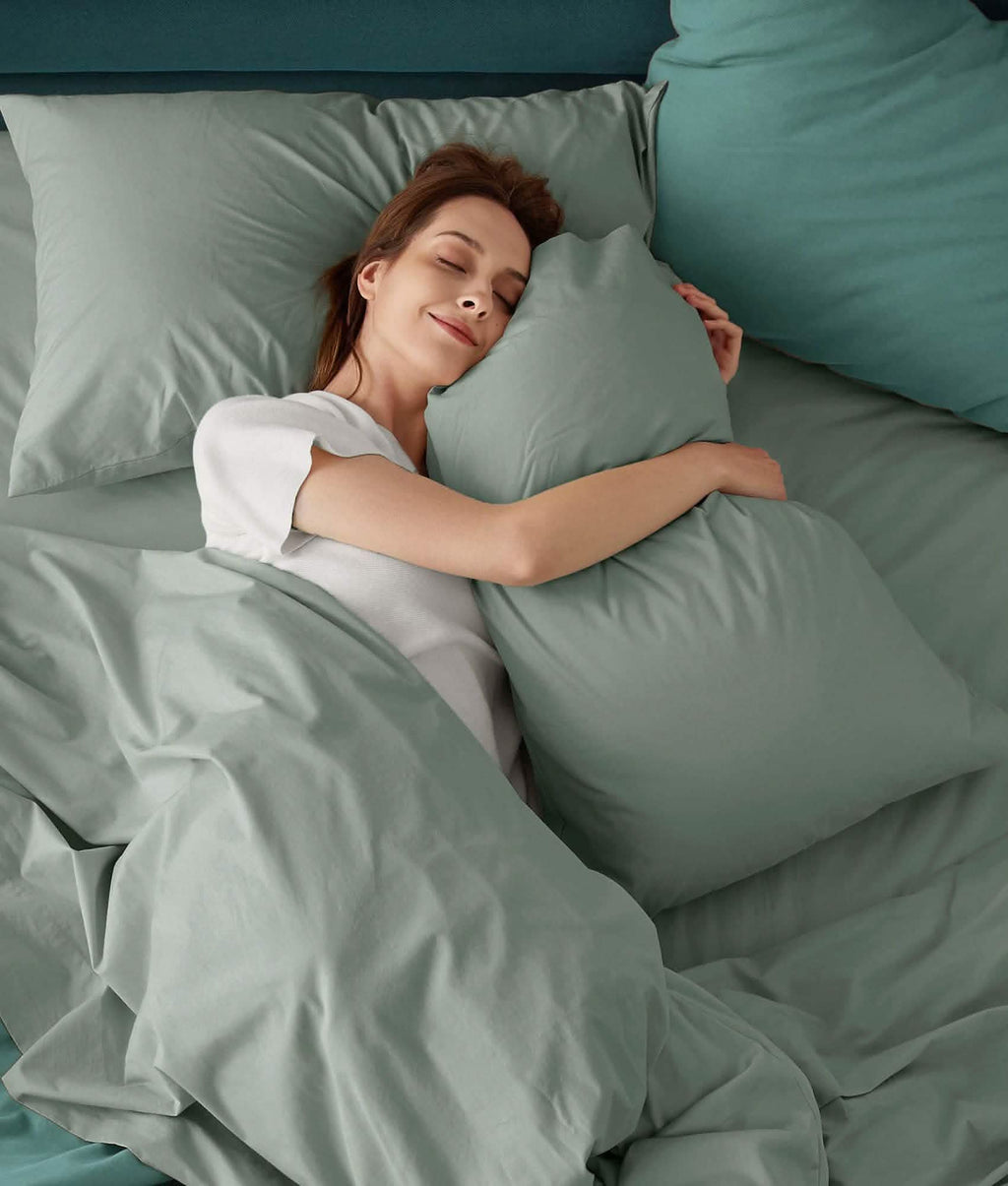 Peaceful woman sleeping on soft, light green 100% cotton percale weave sheet set.