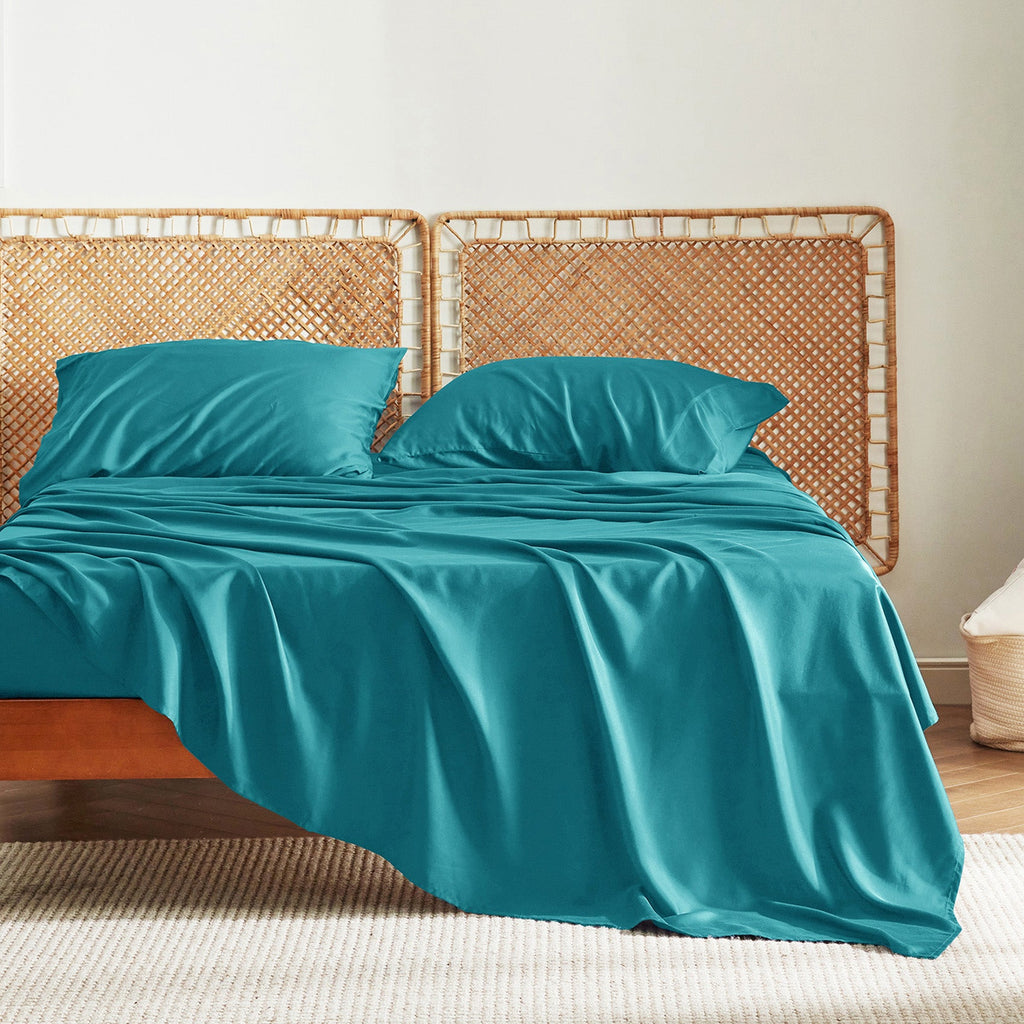 Teal blue GentleSoft bamboo sheet set with pillowcases on a bed, showcasing silky texture and smooth finish.